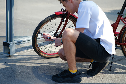 Man pumping bicycle wheel in the park. Man inflates bicycle wheel using a pump. Pumping air into an empty wheel of bike