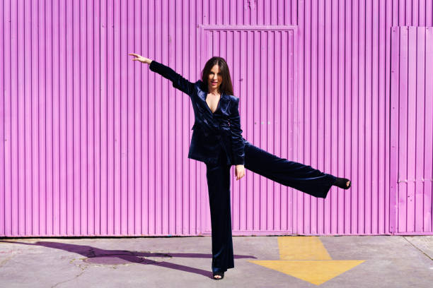 istock Woman wearing blue suit dancing near pink shutter. 1396686898