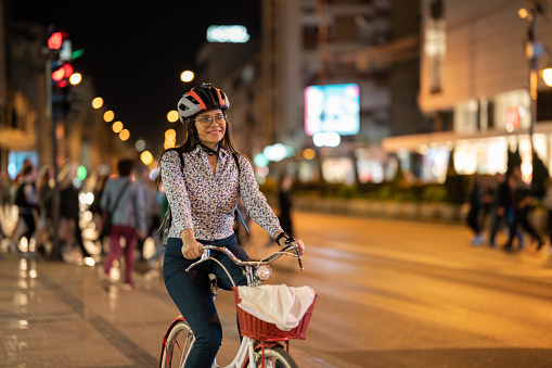 Young woman riding a bicycle in city at night.