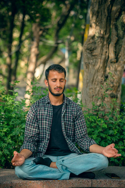 istock Young man does meditation in a public park. 1396686971