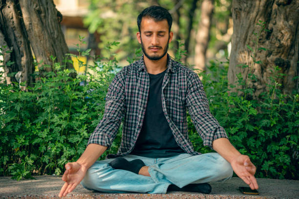 istock Young man does meditation in a public park. 1396686976