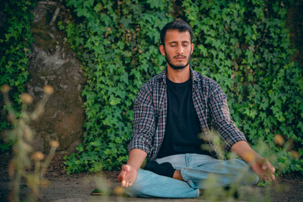 Young man does meditation in a public park.