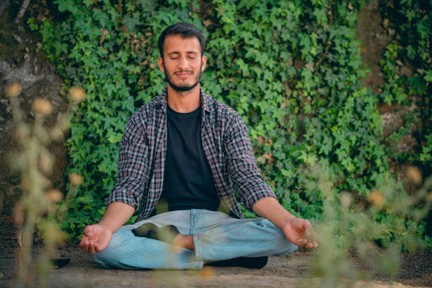 istock Young man does meditation in a public park. 1396687002