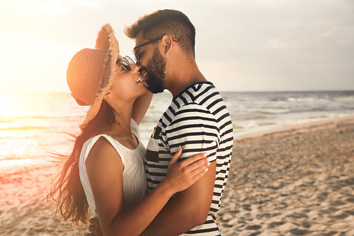 Lovely couple kissing on beach at sunset
