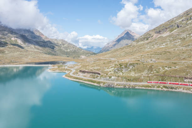 vista de drones del tren suizo que pasa a lo largo del lago bianco en bernina pass, grisones, suiza - white lake fotografías e imágenes de stock