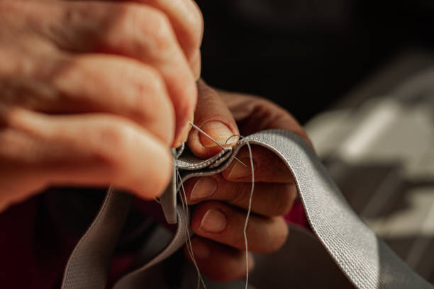 Old asian woman sewing with hands. Needle and thread workshop lesson. Traditional embroidery fine art.