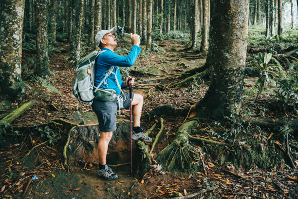istock asian man  drink the fresh water when tracking in the forest 1396690240