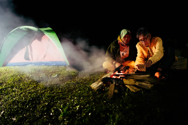 asian couple sitting at camp fire at night