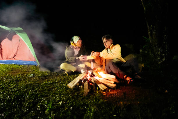istock asian couple sitting at camp fire at night 1396690306