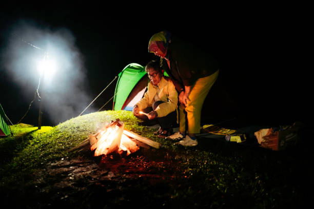 asian couple sitting at camp fire at night asian couple sitting at camp fire at night malay couple full body stock pictures, royalty-free photos & images