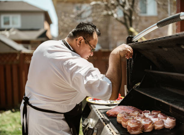 Mature Latin Chef grilling meat on BBQ in the backyard