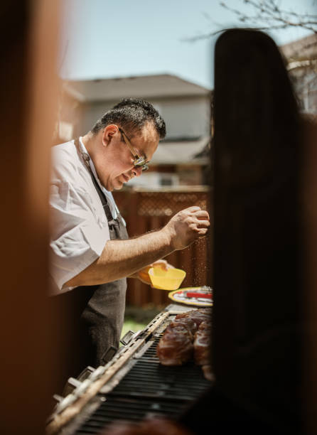 istock Mature Latin Chef grilling meat on BBQ in the backyard 1396690979