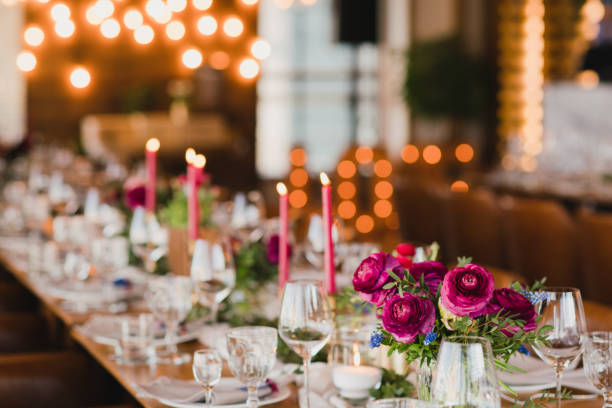 Table setting at the wedding reception. Floral compositions with beautiful ranunculus flowers and greenery, candles, laying and plates on a decorated table.