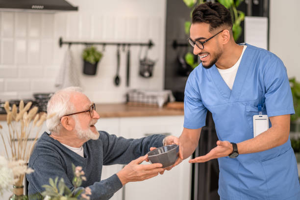 istock Joyful friendly caregiver serving breakfast to an old man 1396691259