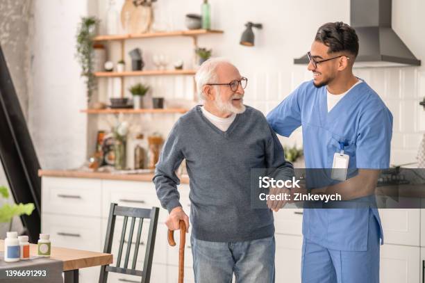 Medical Worker Helping His Patient To Move Around The Apartment Stock Photo - Download Image Now