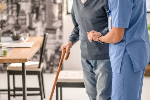 istock Medical worker helping his patient to walk with a cane 1396691298
