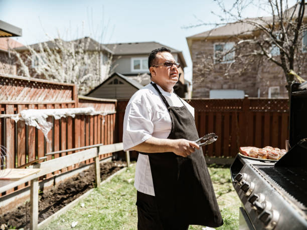 istock Mature Latin Chef grilling meat on BBQ in the backyard 1396693385
