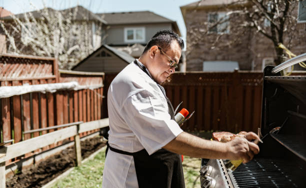 istock Mature Latin Chef grilling meat on BBQ in the backyard 1396693412