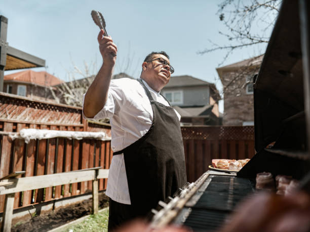istock Mature Latin Chef grilling meat on BBQ in the backyard 1396693468