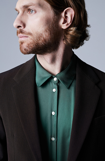 Minimal profile shot of handsome young man wearing trendy suit with teal green silk shirt