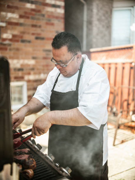 istock Mature Latin Chef grilling meat on BBQ in the backyard 1396693651