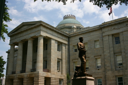 North Carolina Capitol Building in Raleigh, NC with bronze statue in front