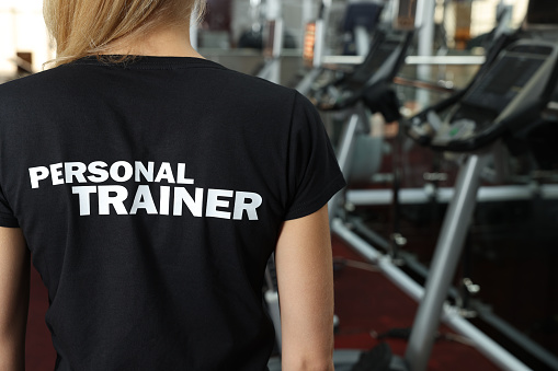 Personal trainer in modern gym, back view