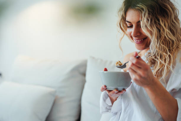 istock Young woman has breakfast in living room 1396697840