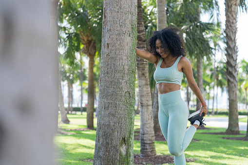Afro Latin woman of average age of 30 years old dressed in sportswear is outdoors doing physical exercises to get in shape