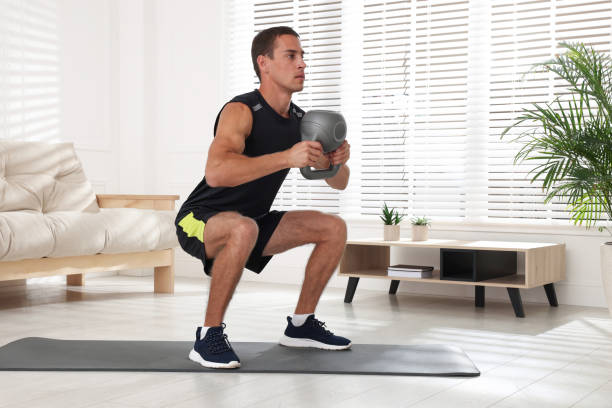istock Handsome man training with kettlebell at home 1396698158