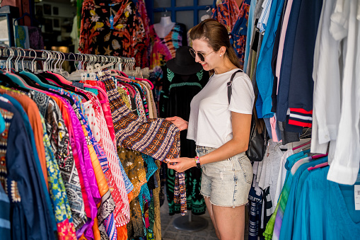 Young woman looking clothing during her shopping in a seaside summer beach boutique