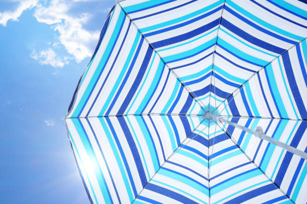 istock Open big striped beach umbrella and beautiful blue sky with white clouds on background 1396699577