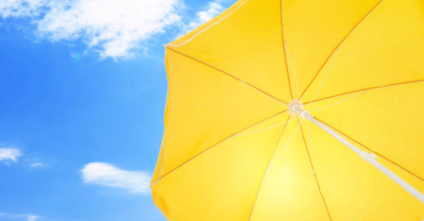 istock Open big yellow beach umbrella and beautiful blue sky with white clouds on background 1396699621