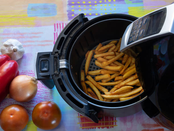 Top view of an air fryer on a table with french fries and vegetables. Top view of an air fryer on a table with french fries and vegetables. Healthy food concept. deep fryer stock pictures, royalty-free photos & images