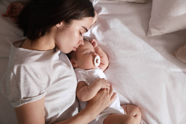 istock Young mother resting near her sleeping baby on bed, top view. Space for text 1396699983