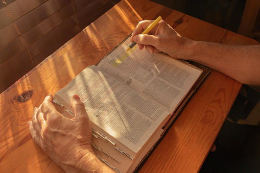 A man is using a marker to highlight scripture while studying his bible