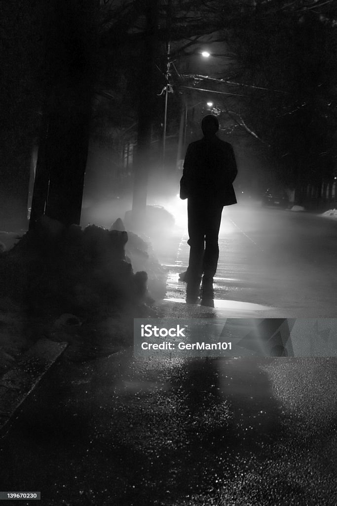 Nightwalk Silhouette of a man in front of a bright light outside on a cold winter night. Escaping Stock Photo