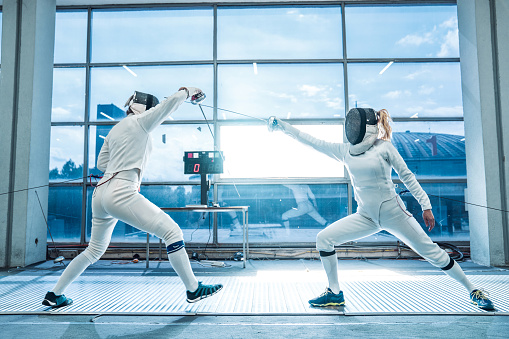 Two female fencers having a training in full fencing suit, they are professional