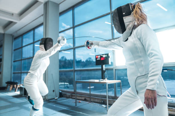 istock Two women wearing fencing suit practicing on professional level 1396703687