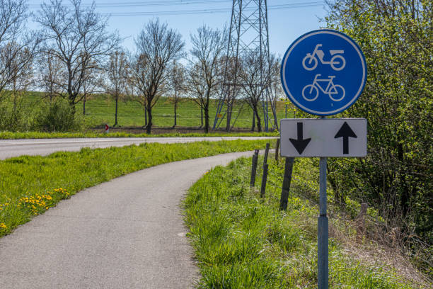 Cycle lane in both directions along a country road, sign indicating: lane for bicycles and mopeds, bare trees in the blurred background stock photo
