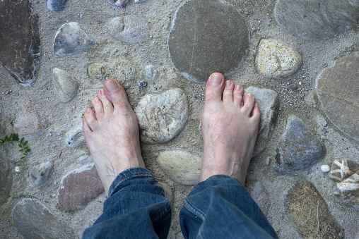 Closeup of barefoot man on pebblestone surface in outdoor
