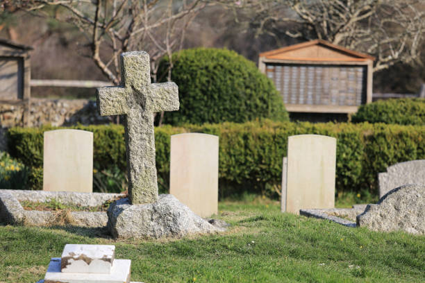 Weathered stone cross in an overgrown rural cemetery under a clear blue sky, mossy gravestone symbolizing faith, remembrance and the quiet passage of time
