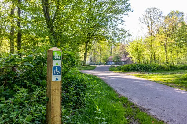 Photo of Hiking sign for disabled people in a park, drawing and words Rolstoel, Scootmobiel means wheelchair and scooter