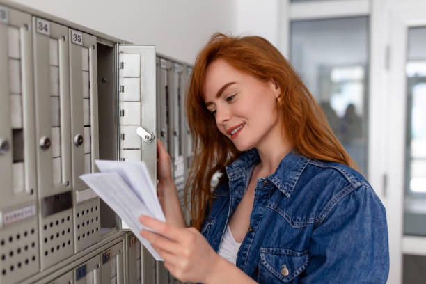 istock Positive casually dressed woman holding new letter from postal delivery, getting her post out of her letterbox 1396706947