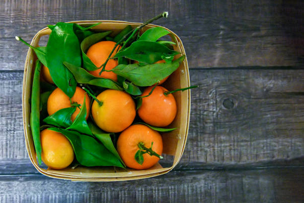 Fresh orange fruits in wooden box on wooden table. stock photo