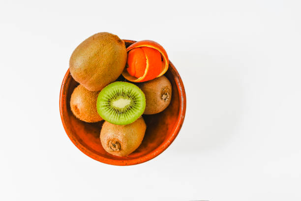 kiwi in a bowl on white background, copy space.