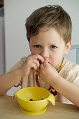 istock Toddler boy eating happily by the table at home 1396708933