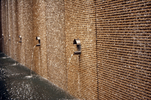 A modern silver water drinking fountain attached to a wall.