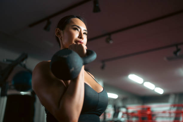 istock Fit woman using weights and training equipment for muscle training in a gym 1396711602