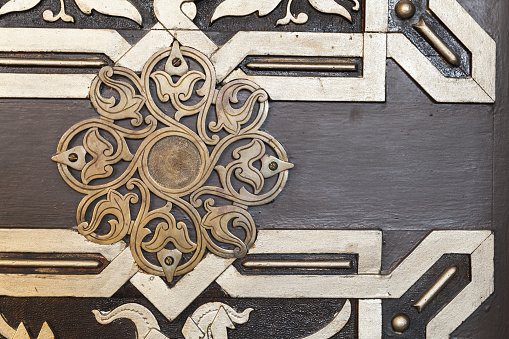 Mosque door decoration with golden ornamental pattern over dark wood background